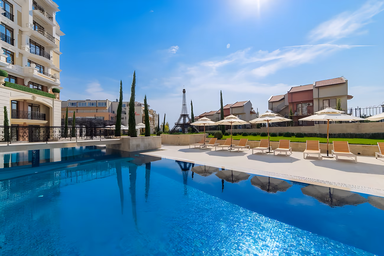 The pool alongside the building, with the model Eiffel Tower among the cypress trees